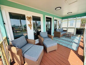 A covered outdoor seating area with wicker furniture and a patterned floor. - 3 Bedroom/Sleeps 7/Sea Isle/pool access (Galveston)
