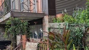 A balcony with a wrought iron railing, a wicker chair, and potted plants. - 144H A Purple Portal Spacious 5-bedroom apartment (New London)