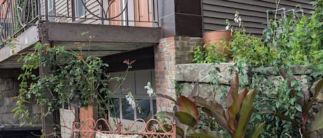 A balcony with a wrought iron railing, a wicker chair, and potted plants.
