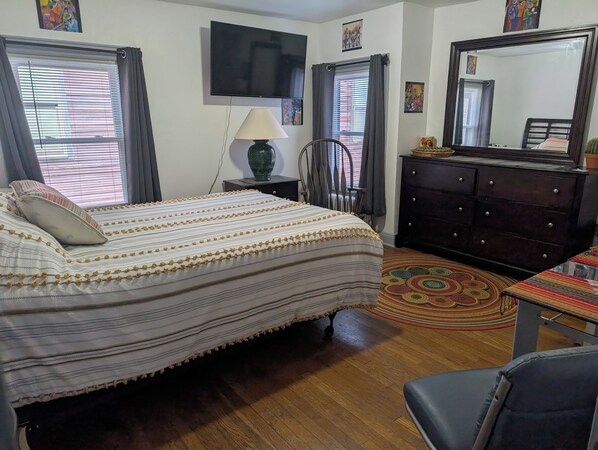 A bedroom with a bed, a dresser, a chair, a lamp, and a TV.