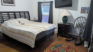 A bedroom with a bed, a TV, a chair, a lamp, and a window with curtains. - 144H A Purple Portal Spacious 5-bedroom apartment (New London)
