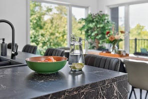 Eine Küchenarbeitsplatte mit einer grünen Schüssel, einem Glasbehälter mit Limettenscheibe und einem modernen Wasserhahn.