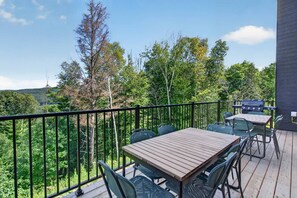 Una terrassa amb taula i cadires, una barbacoa i vistes a una zona boscosa.