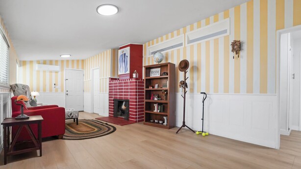 Een woonkamer met een rode bakstenen open haard, gestreepte behang en een rode bank.