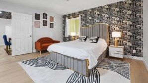 Een slaapkamer met een bed, nachtkastjes, een stoel en een deur.