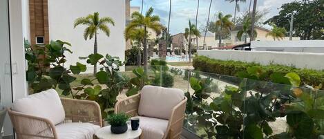 A balcony with wicker chairs, a small table, and a potted plant.