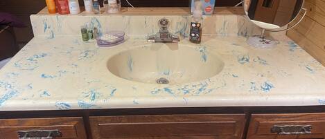 Une salle de bain avec un lavabo en marbre, des meubles en bois et des articles de toilette posés sur le comptoir.
