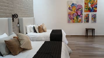 Ein modernes Schlafzimmer mit zwei Betten, einer Ziegelwand, Holzbalken an der Decke und Bildern an der Wand.