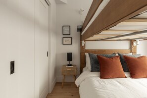 Ein Schlafzimmer mit Etagenbett, Nachttisch, Lampe, gerahmten Bildern und einem kleinen Beistelltisch.