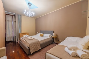 Ein Hotelzimmer mit zwei Betten, einem Holzschrank, einem Nachttisch mit Lampe sowie einem Badezimmer mit Duschvorhang.