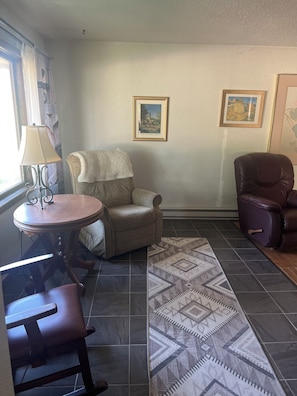 A room with a round wooden table, a cushioned armchair, a patterned rug, and two framed pictures on the wall. - 2-bedroom house in welcoming Lemmon with outdoor space (Lemmon)