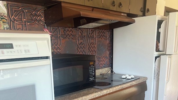A compact kitchen with a microwave, oven, and a refrigerator.
