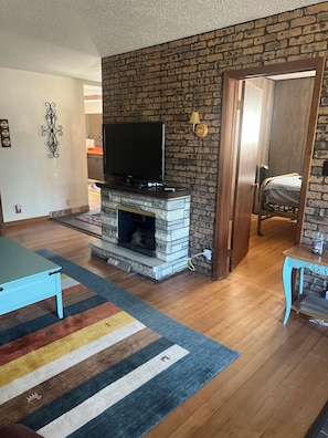 A living room with a fireplace, a television, and a door leading to another room. - 2-bedroom house in welcoming Lemmon with outdoor space (Lemmon)