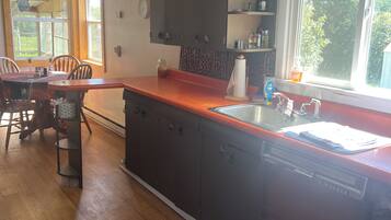 A kitchen with wooden cabinets, a red countertop, a built-in sink, and a patterned rug.