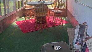 A room with a table and chairs, a red mat, and a grill on the floor.