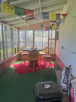 A room with a table and chairs, a red mat, and a grill on the floor. - 2-bedroom house in welcoming Lemmon with outdoor space (Lemmon)