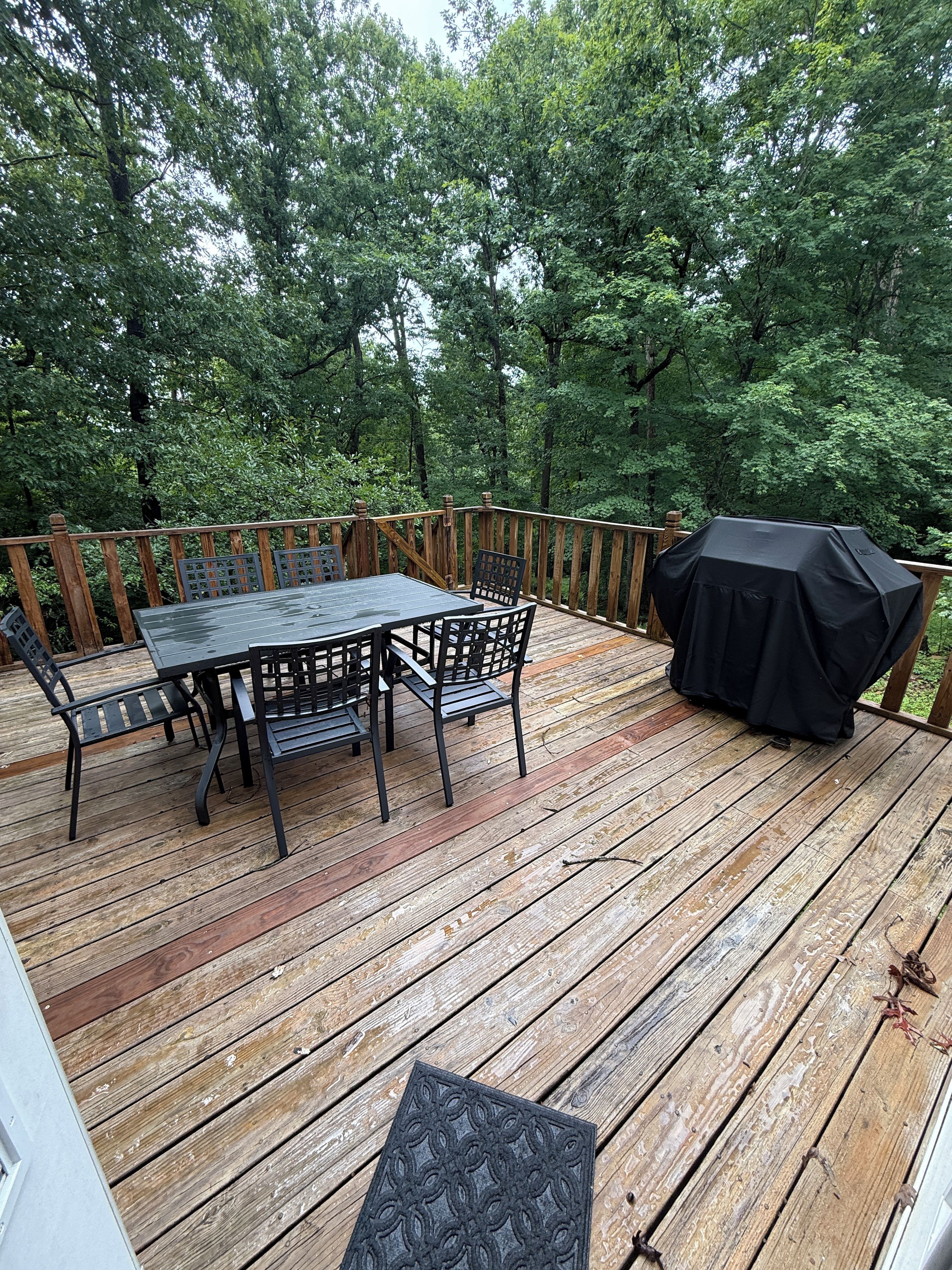 An outdoor deck with a table and chairs, surrounded by a wooden railing.
