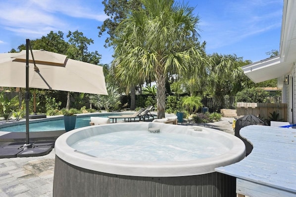 Ein Whirlpool in einem Hinterhof mit einem Pool, Palmen und Gartenmöbeln.
