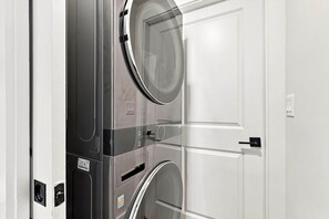 Eine moderne, kompakte Waschmaschine mit Glastür, neben einer weißen Tür platziert.