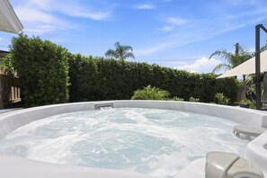 Ein Whirlpool mit Wasserfall, umgeben von einem Holzzaun und üppiger Vegetation.