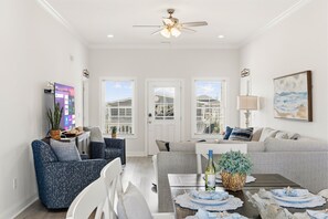 A modern living room with a dining area, white walls, and a ceiling fan. - Waterfront Pool Home · Putting Green · Fishing (North Myrtle Beach)