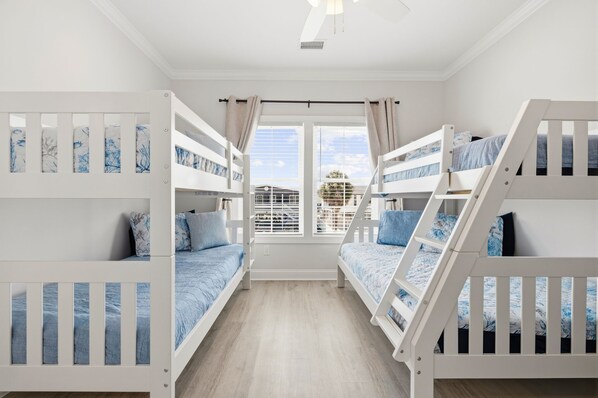 A room with two bunk beds, a window with curtains, and a view of the outside.