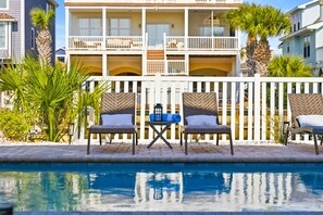 A poolside area with two wicker chairs, a small table, and a pool.