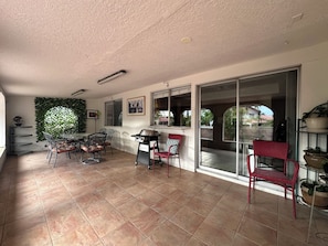 A covered patio area with a dining table, chairs, a grill, and a sliding glass door leading to an outdoor space. - Home Sweet Home: 4-Bed, 3-Bath – Pet Friendly (Las Vegas)