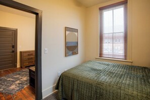 A bedroom with a bed, a window with blinds, a door, and a small table. - Downtown Florence Retreat | Walkable Historic Stay (Florence)