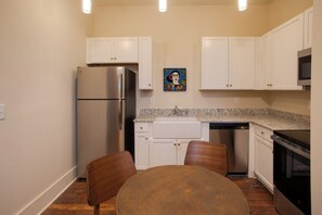 A compact kitchen with white cabinets, a stainless steel refrigerator, a microwave, and a dishwasher. - Downtown Florence Retreat | Walkable Historic Stay (Florence)