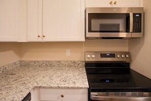 A kitchen with white cabinets, a stainless steel microwave, and a black stove. - Downtown Florence Retreat | Walkable Historic Stay (Florence)