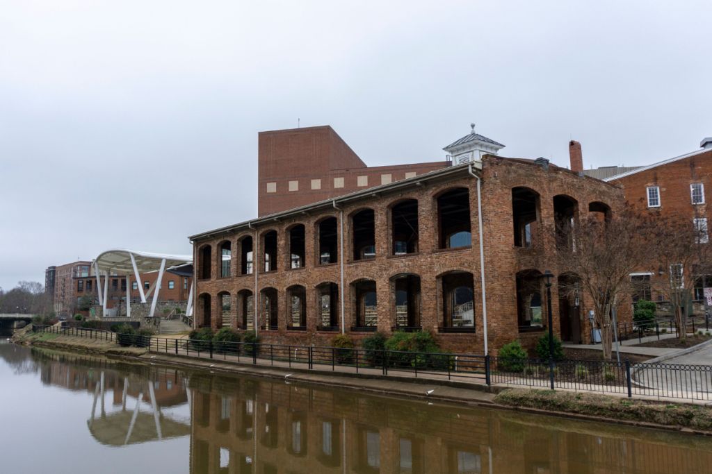 A brick building with arched windows and a reflection in the water.