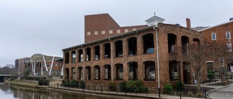 A brick building with arched windows and a reflection in the water.