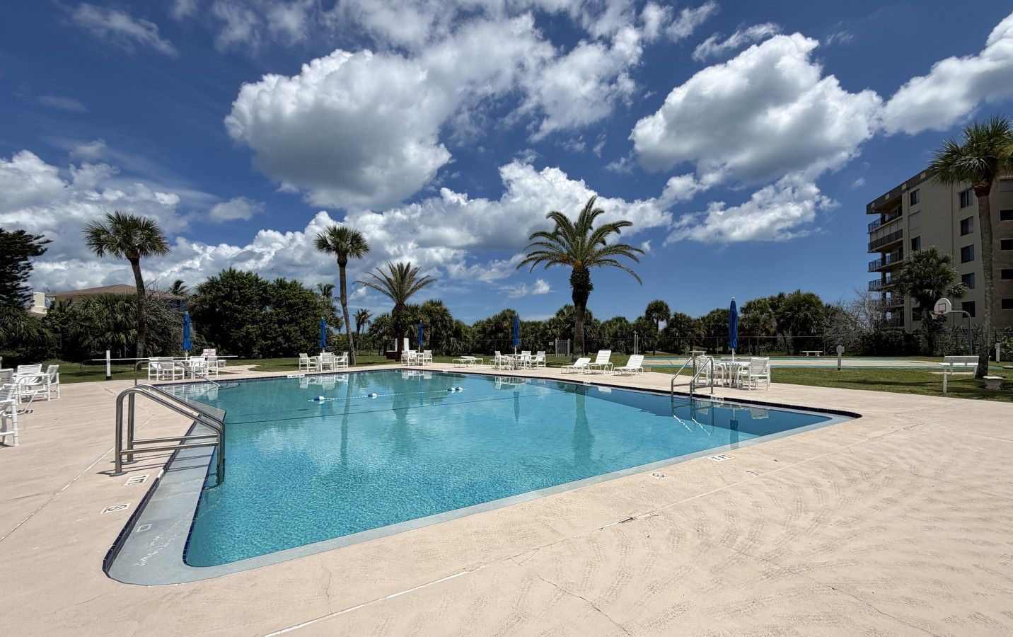 Une piscine rectangulaire à l’eau d’un bleu cristallin, entourée d’une plage de sable.