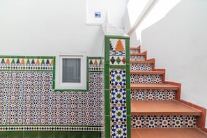A staircase with a patterned tile wall and a window.