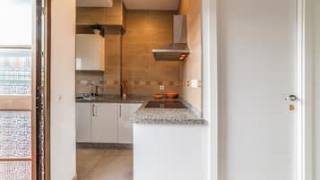 Een keuken met witte kastjes, een granieten aanrechtblad en een roestvrijstalen afzuigkap.