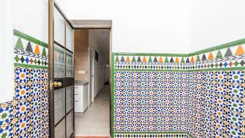 Een gang met wanden van patroontegels en een deur die leidt naar een kamer met een betegelde vloer.