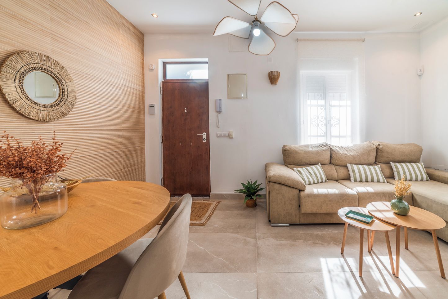 Ein modernes Wohnzimmer mit einem Holzesstisch, einer Couch und einem Deckenventilator.