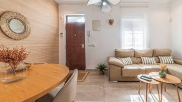 Ein modernes Wohnzimmer mit einem Holzesstisch, einer Couch und einem Deckenventilator.
