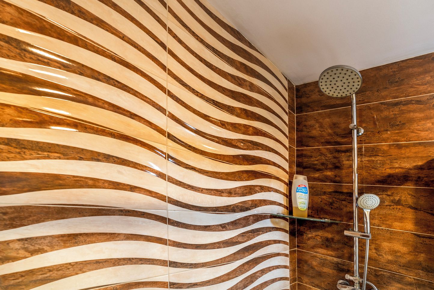 Ducha con diseño moderno, que presenta una pared curva y un cabezal de ducha manual.