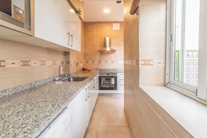 A kitchen with granite countertops, a built-in oven, and a window with a view.