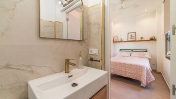 A modern bathroom with a large mirror, a white sink, and a shower area.