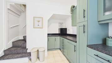 A kitchen with light green cabinets, a black refrigerator, and a framed picture on the wall.