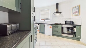 Een moderne keuken met een ingebouwde toaster, een magnetron, een oven en een vaatwasser.