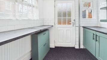 A kitchen with white tiled walls, a white door, and green cabinets.