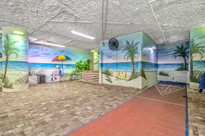 A beach-themed interior with murals, a reception desk, and a shuffleboard table. - Dunes Village 452 - Updated Oceanfront 2BR (Myrtle Beach)