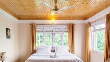 A room with a wooden ceiling, a bed, a bench, a table, and a chair.