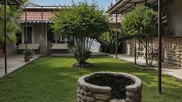 Un patio con un hogar de piedra, un banco y un pequeño árbol.