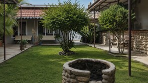 Un patio con un hogar de piedra, un banco y un pequeño árbol.