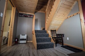 Eine Treppe mit Holzgeländern führt zu einem Erkerbereich, ein Feuerlöscher und ein Stuhl sind ebenfalls zu sehen.